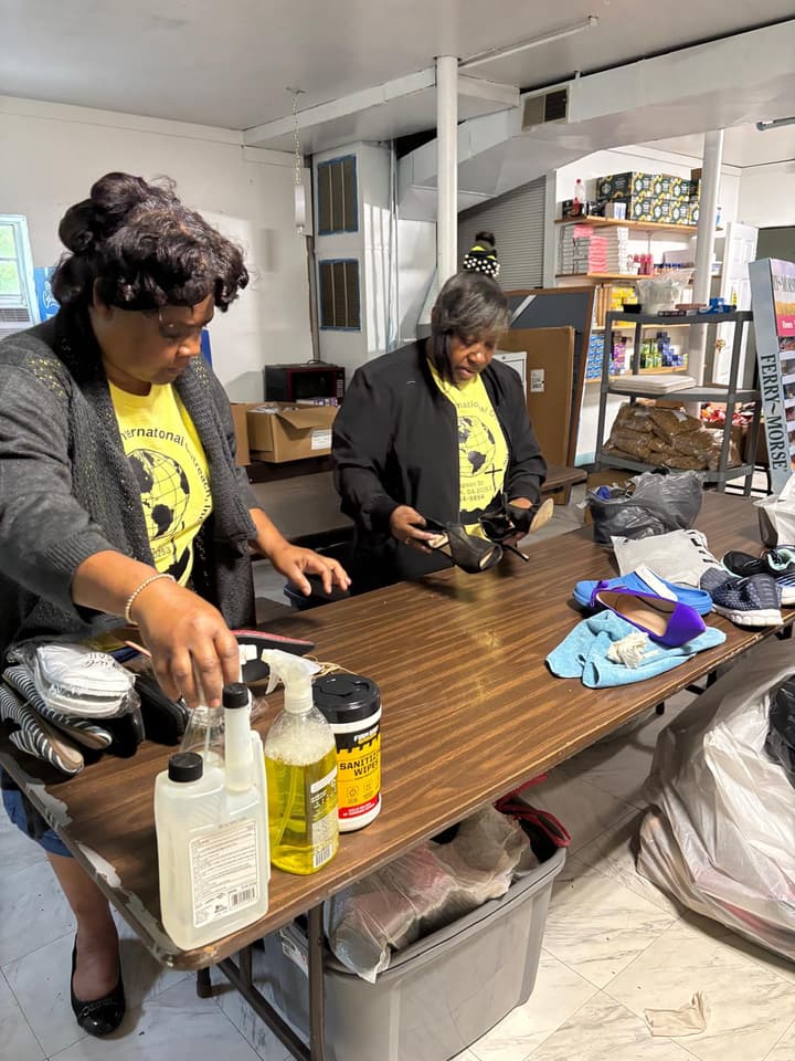 Two volunteers clean and sort donated shoes for the clothing closet.